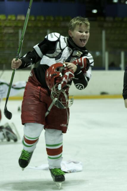 Völlig losgelöst und aufgedreht vor Siegesfreude sammelt er seine Eishockeyausrüstung wieder ein.