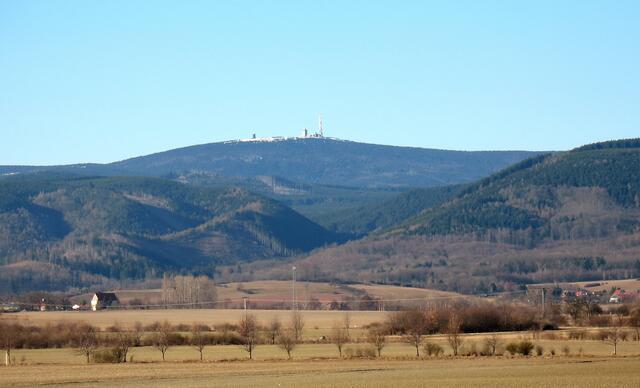 Weit überragt er alle anderen Harzberge. Ansicht von Norden. Der Taleinschnitt vorne ist das Ilsetal. Rechts einige Häuser von Ilsenburg. Vor der Wende qualmten dort die hohen Schlote des Hüttenwerkes.