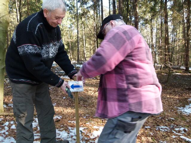 Horst Erdel und Holger Bötel bringen ein Schild an der 7 km langen Wanderstrecke an.