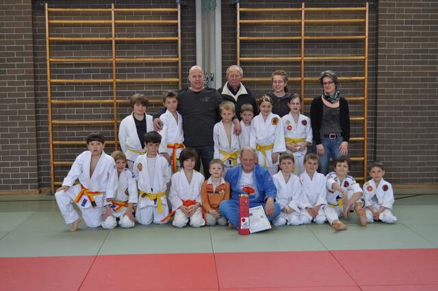 SCUG-Abteilungsleiter Mike Jäger und sein Vorgänger Diethard Schönherr (Bildmitte stehend) gratulieren dem Jubilar (sitzend im blauen Judogi)