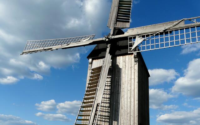 Die Bockwindmühle Wettmar strahlt im Sonnenschein. Segelflügel mit eingerollten Segeln.
