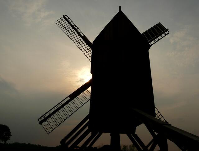 Malerisch zeichnet sich die Silhouette der Mühle gegen den Abendhimmel ab.