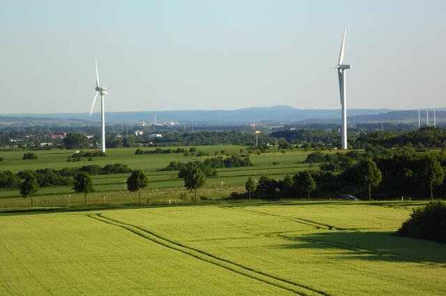 Der Blick geht nach Süden auf das Leine- und Weserbergland. Rechts neben dem linken Windrad die Zuckerfabrik bei Barnten. Rechts neben dem rechten Windrad der Marienberg mit der Marienburg.