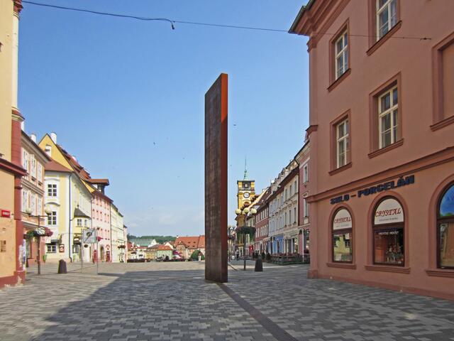 Marktplatz von Cheb (13. Jhdt.).
Denkmal in Form einer Metallsäule.
Von hier aus führt ein Metallband bis zum Bahnhof.
Darauf sind Inschriften aller geschichtlichen Ereignisse der Stadt Eger eingraviert, angefangen von der erstmaligen urkundlichen Erwähnung der Stadt (1061) bis in die Neuzeit.