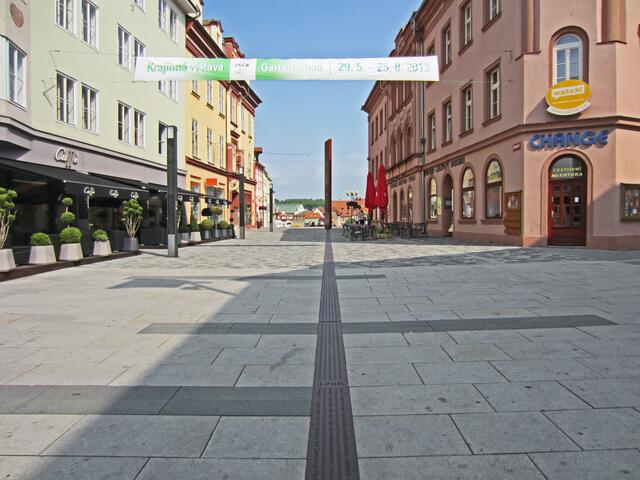 Marktplatz von Cheb (13. Jhdt.).
Denkmal in Form einer Metallsäule.
Von hier aus führt ein Metallband bis zum Bahnhof.
Darauf sind Inschriften aller geschichtlichen Ereignisse der Stadt Eger eingraviert, angefangen von der erstmaligen urkundlichen Erwähnung der Stadt (1061) bis in die Neuzeit.