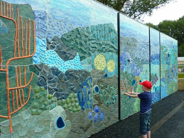 Über die Wand läuft Wasser. Der Junge hatte viel Freude daran, es mit seinen Händen aufzufangen.