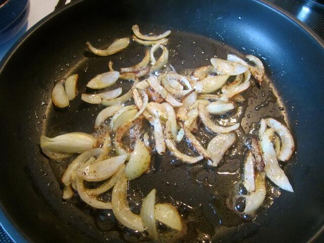 Die Zwiebel pellen, halbieren und in Scheiben schneiden - fällt beim Braten auseinander