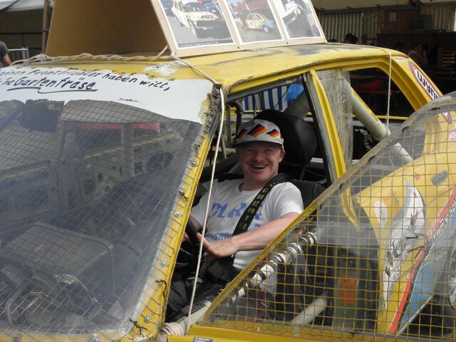 Da sieht man, wie dieser Mann sich freut. Er darf in einem Crossauto sitzen.