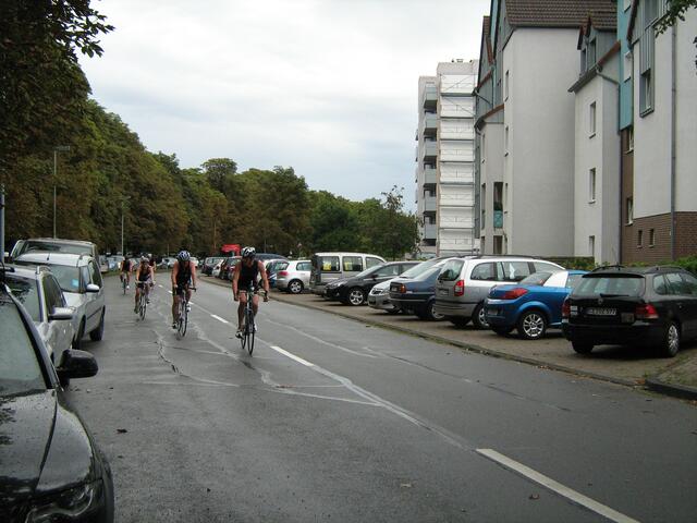 Hier kommt ein Grüppchen auf regennasser Straße zur Wechselzone.
