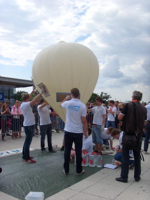 Der Ballon wird, bis er vollständig aufgefüllt ist, von allen Seiten mit Pappdeckeln in Balance gehalten.