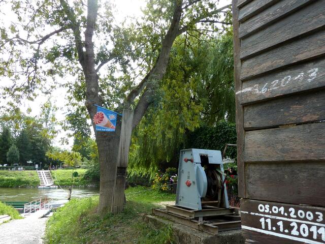Der Fährmann führt seine Fähre am Seil entlang. An der Wand sind die Hochwasserpegelstände zu sehen. Der vom 3.6.2013 ist mit Abstand der höchste.