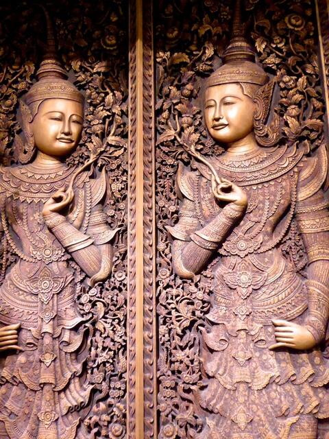 Schutzgottheiten verzieren eine Palasteingangstür. Das hölzerne Kunstwerk hat seinen Ursprung 1910 in Chiang Mai im Norden Thailands.