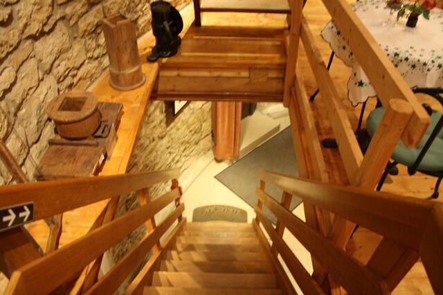 Treppenabgang zum Erdgeschoß, dort befindet sich eine kleine Küche, (Kuchen)-Theke und moderne sanitäre Anlagen