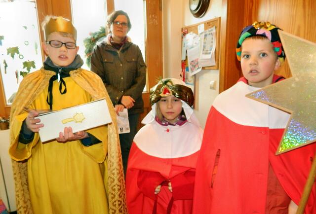 Die Sternsinger Felix, Janne und David. Im Hintergrund führt die Gruppe Frau Hellmann.