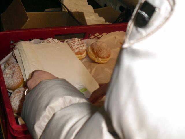 Fleißige Hände verpacken die frischen Krapfen