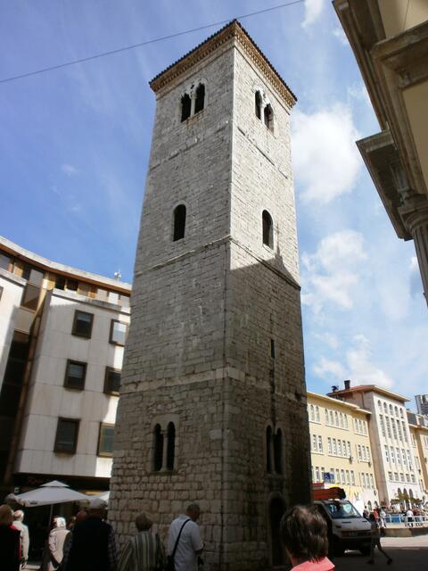 Vor uns steht der „schiefe Turm von Rijeka“. Er ist der Campanile der Kirche Maria Himmelfahrt. Der mittelalterliche Turm hat sich ca. 40 cm geneigt. Unter dem Turm befinden sich römische Thermen, was wohl der Grund für das Neigen ist.