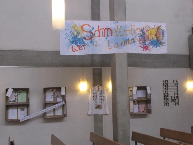 Die Gedichte stecken in bescheidenen Kartons. Ein buntes Transparent von Poetin Obermaier ziert temporär das Kirchenschiff. | Foto: Thomas Schwarz