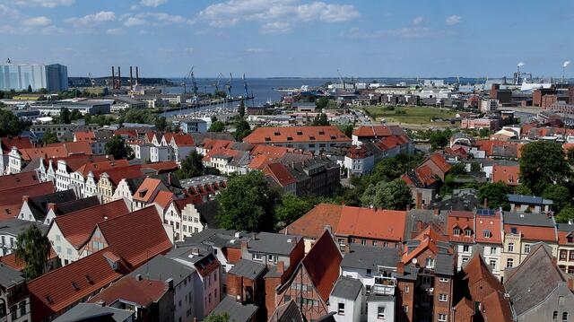 Im Vordergrund läuft die Lübsche Straße quer durch das Bild; im Hintergrund (von links) sind die Werfthalle, der Westhafen, die Wismarbucht und die Insel Poel zu erkennen.