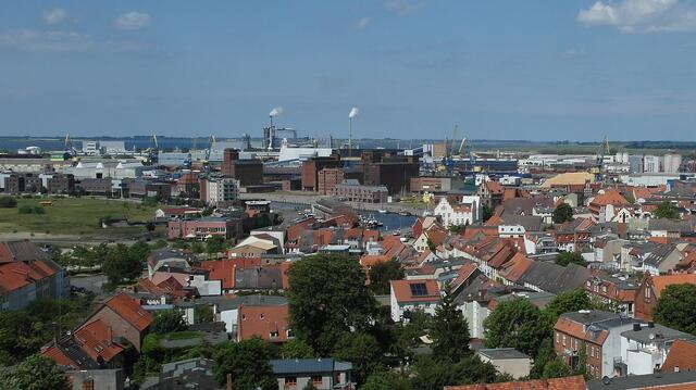Die Sicht auf den Alten Hafen (Bildmitte) mit den historischen Speichergebäuden, im Hintergrund der Seehafen und das Industriegebiet sowie die Insel Poel am Horizont.
