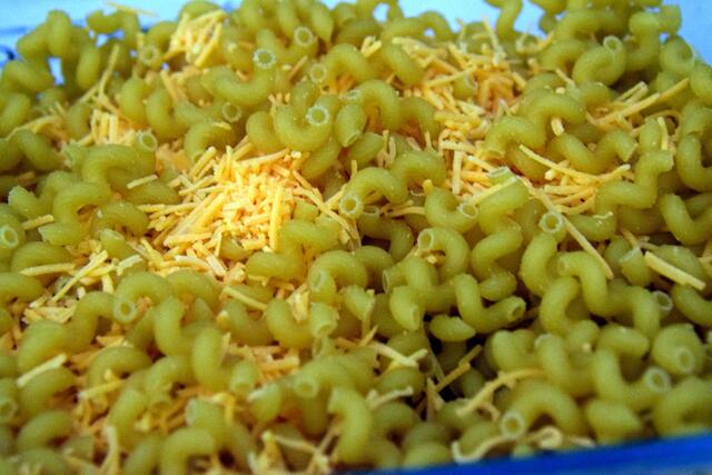 ungekochte Nudeln mit Käse,  Salz und Pfeffer in der Auflaufform vermischen