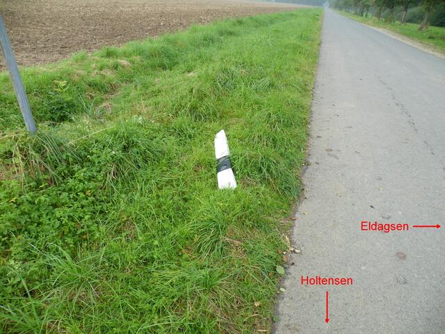 2. "Sein Grab"; der Leitpfahl liegt nun am Feldweg jenseits der K208 (Klosterstraße).