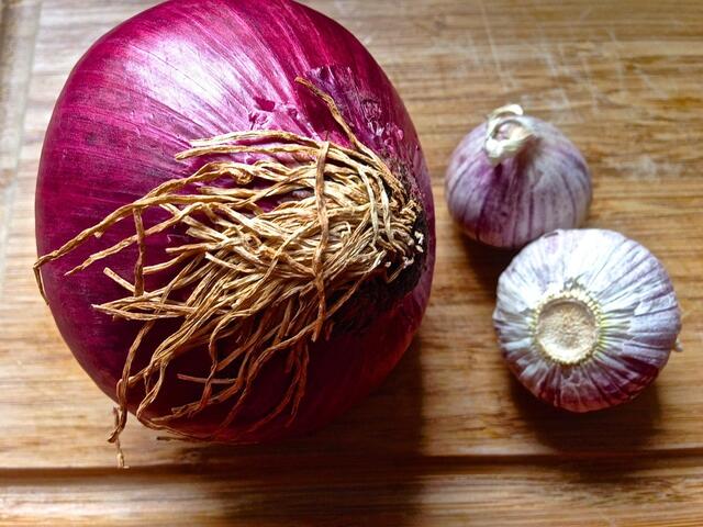 Eine kleine oder halbe große Zwiebel und 2 Knoblauch pellen und ganz fein schneiden