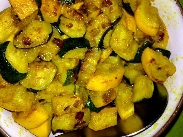 Gelbe und grüne Zucchini mit etwas roter Zwiebel in selbstgemachem Knoblauchöl mit Kurkuma und etwas Salz angebraten