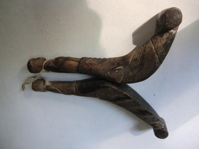 Mutter und Vaterfiguren krönen diese beiden hölzernen Haken mit denen Reishalme auf dem Feld schnell und sicher zu Ährenbündeln zusammengebracht werden können.
