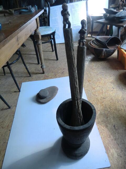 Im Haus der Kulturen wird die Ausstellung von Essgerät vorbereitet: Hinten ein Mahlstein aus der Jungsteinzeit, davor alte  Getreidestampfer aus Gabun
