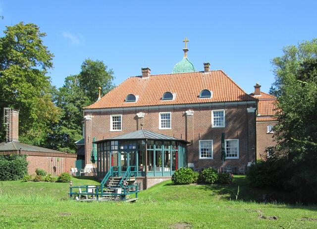 Ein Restaurant nutzt den Sielhof, dessen Rückansicht sich aus dem schönen Parkgelände zeigt.