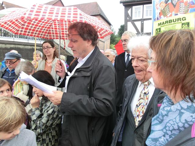 Schulkinder der Waldschule Wehrda, Stadträtin Dr. Weinbach, Pfarrer Wehrmann von der Martinsgemeinde und das Ehepaar Orbach (von links nach rechts) hören u. a. die Dankesworte an die Spender der Stolpersteine, ohne die die Verlegung nicht möglich gewesen wäre (siehe Broschüre). | Foto: Barbara Wagner
