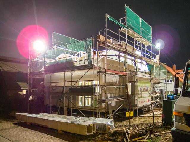 Am Abend des ersten Montagetages ist der Rohbau weit gediehen. Die Baustelle ist taghell ausgeleuchtet.