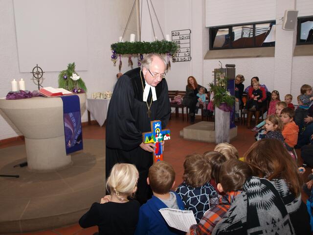 Regionalbischof Michael Grabow zeit den Kindergartenkindern das Kreuz, das er als Geschenk zur Einweihung mitgebracht hat