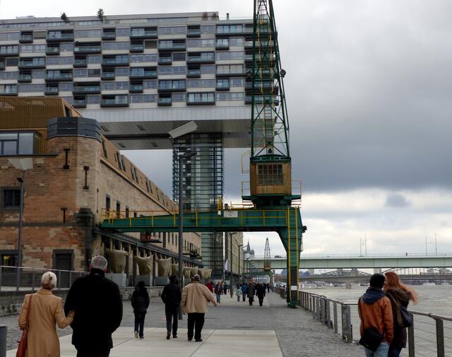 Viele Besucher Kölns flanieren entlang der Rheinaupromenade. Eines der drei Kranhäuser wurde als Wohnhaus konzipiert.