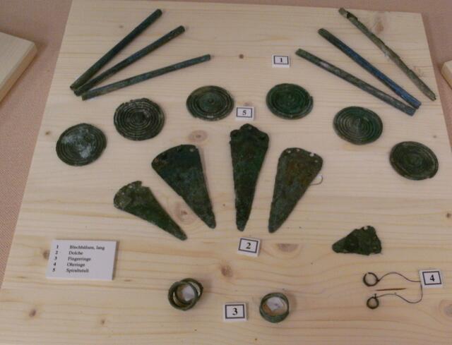 Bronze - Dolche, Fingerringe, Scheibenfibeln /Tutuli), und Spangen/Nadeln / Ausstellungsartefakte im Museum Königsbrunn