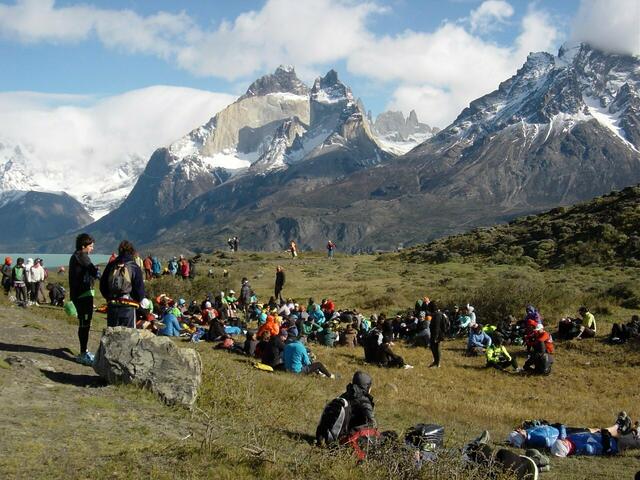 Sammelplatz der Halbmarathonläufer 200 Meter vom Start entfernt. Die Athleten suchen in einer Mulde und hinter Büschen Schutz vor dem kalten Wind. Berge, im Vordergrund: Cuernos del Paine (Mitte), 2.600 m und Monte Almirante Nieto (rechts), 2640 m. Dazwischen im Hintergrund: Spitzen der Torres del Paine, 2.850 m.