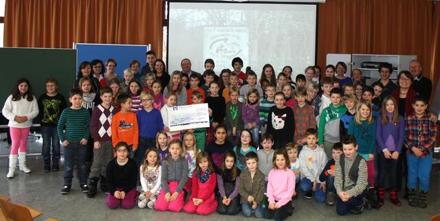 Ein großer Scheck für Tansania: Gruppenbild mit den Beteiligten des sozialen Projekts in der kleinen Aula des Justus-von-Liebig-Gymnasiums.