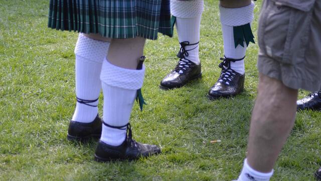 Socken, die von Strumpfhaltern ( Flashes) gehalten werden. Im rechten Strumpf steckt außen ein kleines Messer (Sgian Dubh), die Schuhe heißen Ghillie Brogues.