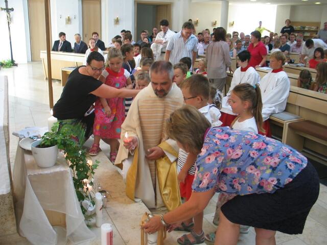 Die Kinder hatten ihre eigenen Taufkerzen mitgebracht, die am Licht der Osterkerze entzündet wurden und zur Figur des Kirchenpatrons Ulrich gestellt wurden.