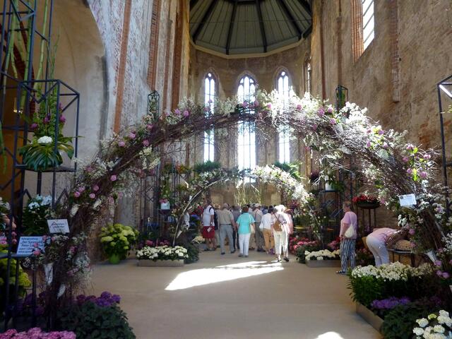 Blumenbögen, bunte Blumen und viele Menschen in der ehemaligen Kirche