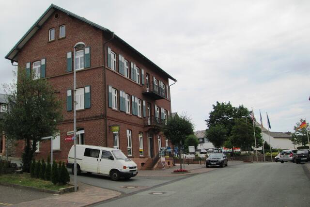 Wer aus der Richtung Biedenkopf oder Bad Berleburg die erste Zufahrt Richtung Battenberg nimmt, kommt auf der Kreisstraße 119 am neuen Penny-Markt vorbei und nach etwa 1 Kilometer an die genannten Wegweiser. In die Einfahrt, aus der der weiße Bus kommt, kann derjenige fahren, der sein Auto beim Alt Battenberg parken will und den Weg zum Treffpunkt zu Fuß geht.