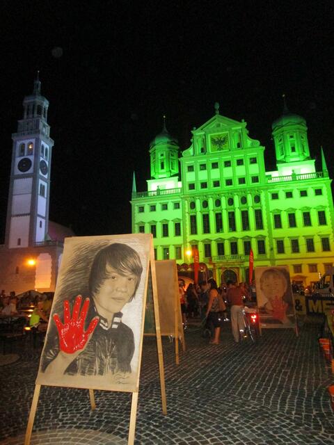 Tomé s Rote Hand Porträt von Jonas vor erleuchteter Rathausplatzkulisse in Augsburg