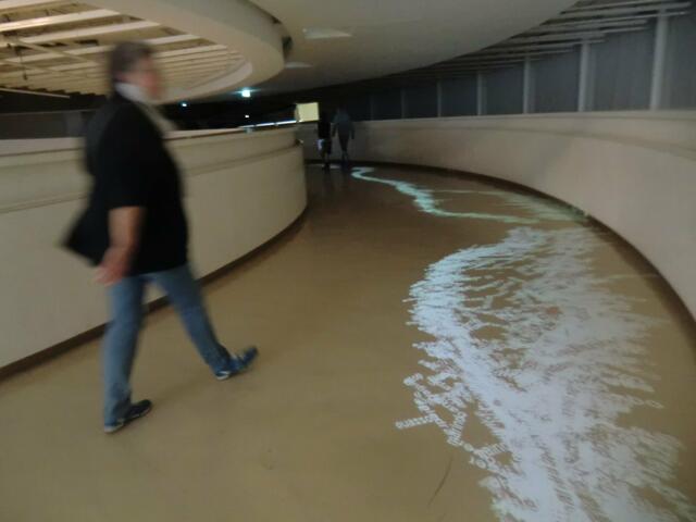 Vom Fluss von Zeit und Raum erzählt diese Installation auf dem absichtlich langen Weg zu den Kulturen der Fremde: die Namen von heutigen und schon längst untergegangenen Völkern plätschern als Videoprojektion aus den Beamern die Rampe hinunter. Namen erscheinen und verschwinden wider.