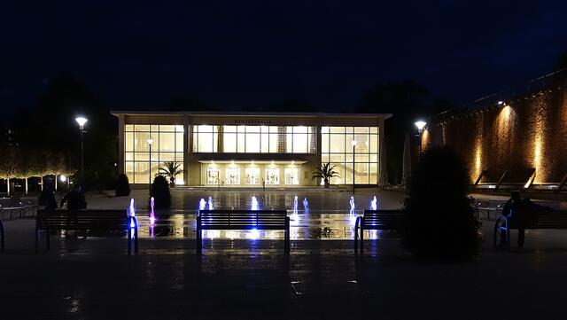 Der Brunnenplatz mit den beleuchteten Fontänen, im Hintergrund die Konzerthalle. Foto: Helmut Kuzina