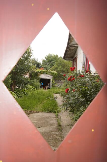 Ein Blick durch ein winziges Fensterchen in Rumänien in eine Welt, die sich von der Straße davor extrem unterscheidet.