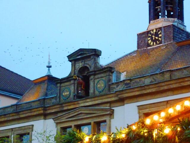 Zur vollen Stunde öffnet sich im Dach ein Türchen und die kleine Trompeterfigur tritt hervor. Es wird Weihnachtsmusik gespielt. Zuvor hat der Glockenschlag einen Vogelschwarm aufgeschreckt.