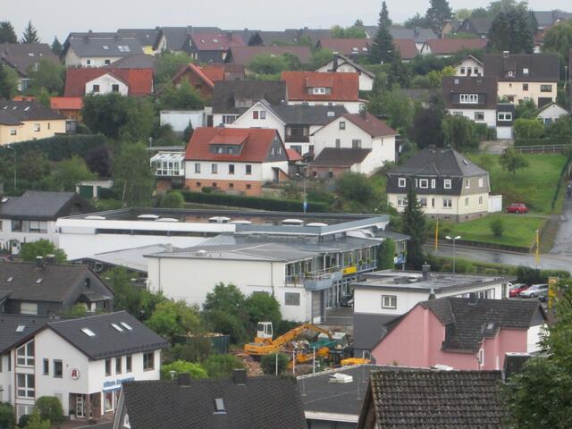 Hier die Lücke (mit Bagger) zwischen der Apotheke (links vorne) und dem Autohaus (Bildmitte).