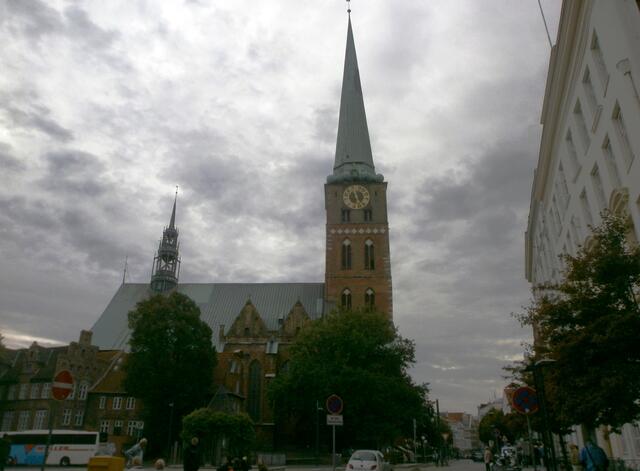 Wir sehen die Jacobikirche. St. Jakobi ist eine der fünf Hauptkirchen der Lübecker Altstadt. Sie wurde 1334 als Kirche der Seefahrer und Fischer geweiht. Seit 2007 ist die nördliche Turmkapelle der Kirche Nationale Gedenkstätte für die zivile Seefahrt. Dort befindet sich eine Gedenkstätte für die auf See gebliebenen Lübecker Seeleute. Hier steht auch das Wrack eines Rettungsbootes der 1957 gesunkenen Viermastbark Pamir. Bei deren Untergang kamen 80 der 86 Besatzungsmitglieder ums Leben. St. Jakobi blieb als