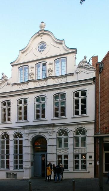 Direkt in der Straße hinter dem Kontor sehen wir ganz in weiß das Thomas-Mann-Haus oder auch Buddenbrookhaus -  Dort befindet sich ein Museum mit zwei festen Ausstellungen: „Die Buddenbrooks“ und „Die Manns“. Weiter gibt es noch eine Etage für wechselnde Sonderausstellungen.