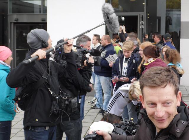 Ein Fernsehteam interviewt die schon lange wartenden Fans.